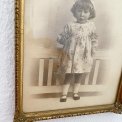 Black and white photo of a little girl in a gold frame, dated 1928