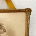 Black and white photo of a little girl in a gold frame, dated 1928