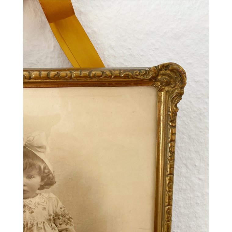 Black and white photo of a little girl in a gold frame, dated 1928