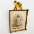 Black and white photo of a little girl in a gold frame, dated 1928